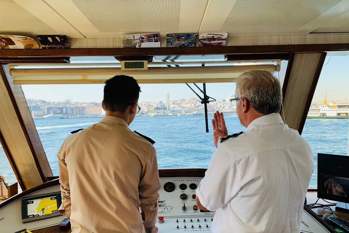 Two seafarers reviewing navigation on a ship bridge.
